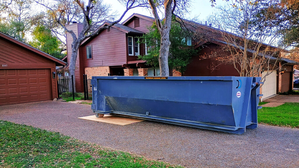 A large roll-off dumpster in a driveway